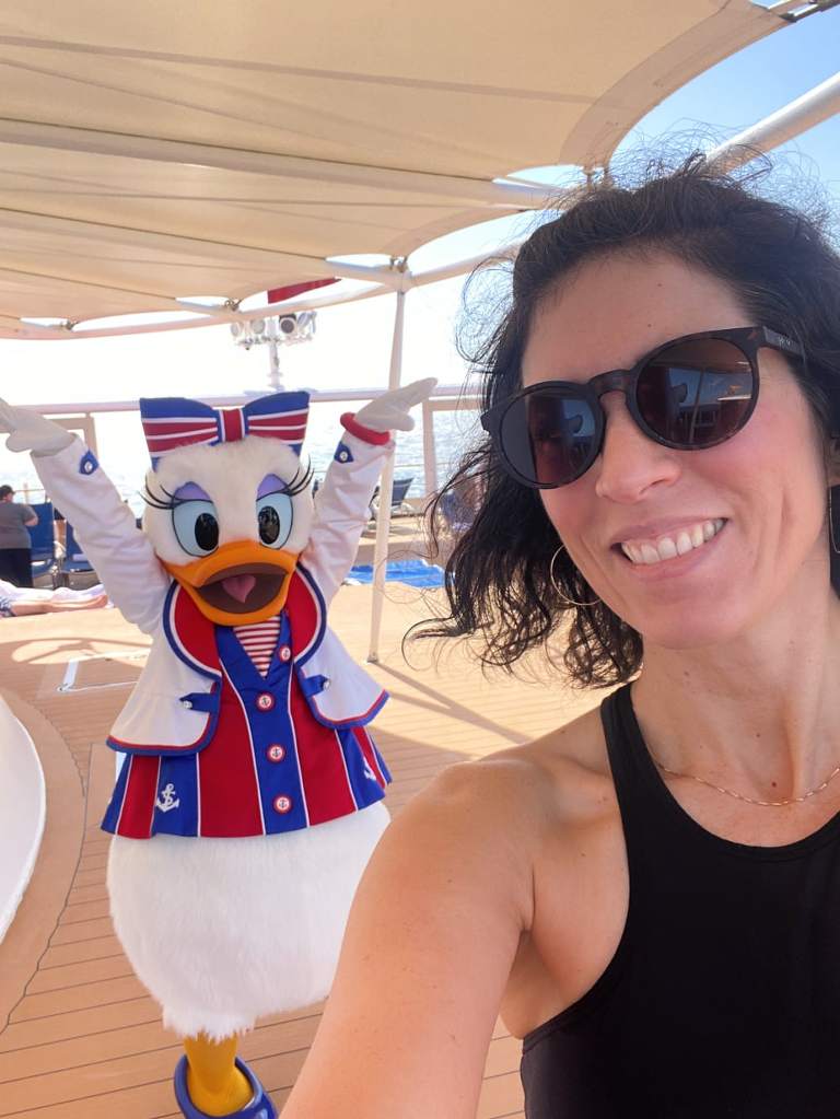 Me, a white woman with dark shoulder length hair, taking a selfie with Daisy Duck posing in the background.